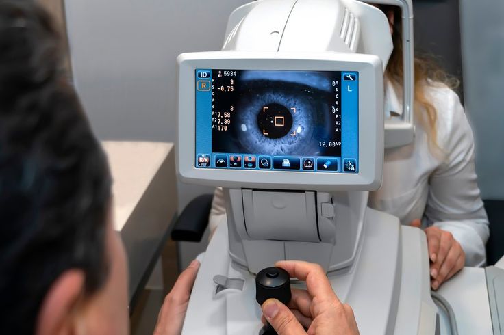 lady looking at refractometer eye testing machine in ophthalmology focus on the eye on the screen